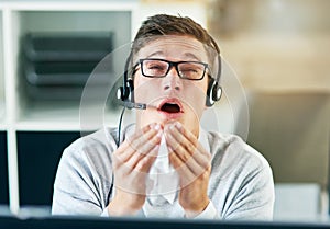 All this sneezing is keeping me from succeeding. a young call centre agent sneezing while working in an office.