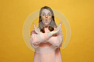 All sold out. Amazed young girl showing stop gesture crossed her palms on yellow studio background. Big sale