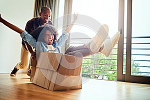 We all are still children deep inside. Shot of a cheerful young woman inside of a cardboard box being pushed by her