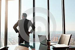 All it takes is an ambitious mind. Rearview shot of a young businessman looking out the window in an office.