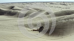 All terrain vehicle ATV driving over sand dunes in desert, aerial view