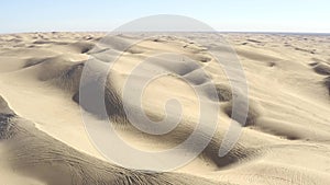 All terrain vehicle ATV tracks on sand dunes in vast desert, aerial view