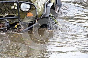 The all-terrain vehicle drove into a large water sharpens the wheels and the front part with headlights