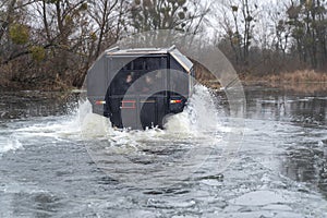 All-terrain vehicle with passengers crossing an icy river