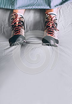 All time ready for trekking. Hiker sleeping in comfort trekking boots. Footwear on the bed sheet background concept image