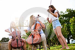 All together now. a cheerful young mother and her two daughters playing classical string instruments together while