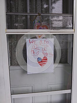 We are all in this together patriotic flag drawing taped to glass  of storm door a  storm door below a ripped screen