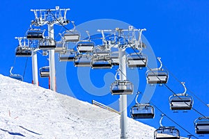 All vacant are the chairs of cableway ski lift line in Gorky Gorod mountain ski resort in Sochi, Russia, viewed against blue sky a