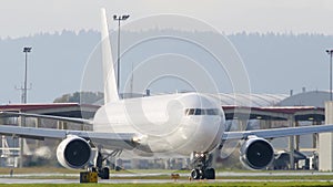 All white widebody cargo airplane navigating towards the runway at the airport to take off.