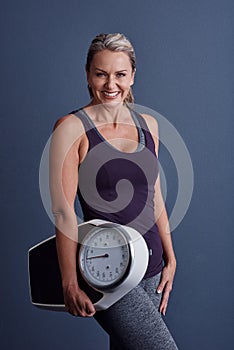 All you need is a goal and a scale. Studio portrait of an attractive mature woman holding a weightscale against a blue