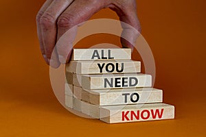 All you need to know symbol. Wooden blocks with words All you need to know on orange background, copy space. Businessman hand.