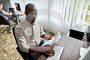 All you need is Trade. High-angle view of young trader sitting by desk and studying analytical reports while working in