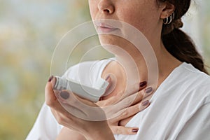 Allergic Asthma. A woman experiencing an asthmatic attack, holding an inhaler with medication to her face. Close up of hands.