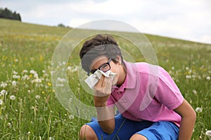 Allergic boy with glasses blows his nose