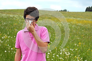 Allergic boy with glasses and pink t-shirt blows his nose