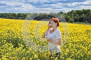 Allergic to pollen and flowering season, a girl sneezes in a flower field