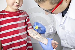 An allergist doctor makes a skin test for allergies. The boy is being examined in the laboratory, waiting for a reaction to