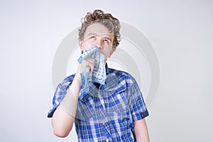 Allergy Boy Child with runny nose holding a handkerchief. Teenager is having bad health and standing on white studio background al