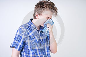 Allergy Boy Child with runny nose holding a handkerchief. Teenager is having bad health and standing on white studio background al