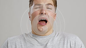 Allergy. Close up of young man sneezing and blowing nose with paper tissue, slow motion