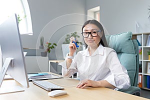 Allergy, feeling unwell at the workplace. A young Asian woman in the office looking at the camera