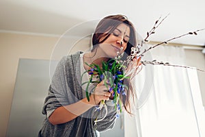 Allergy free. Happy woman smelling bouquet of flowers after recovery on kitchen. Seasonal allergy concept