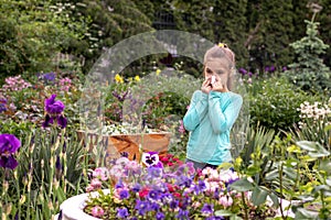 Allergy. A little girl blows her nose into a handkerchief, shocked by an allergic reaction to blooming flowers near a