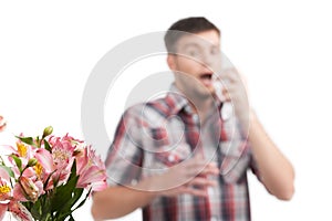 Allergy man blowing his nose in tissue paper.