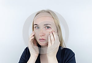 Allergy to cosmetics. The girl looks at the pimples around her eyes that appeared after using toxic cosmetics. Red spots on woman