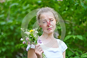 Allergy. Woman squeezed her nose with a clothespin, so as not to sneeze from the pollen of flowers photo