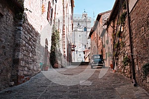 An alley of an Italian medieval village with an old car parked Gubbio, Umbria, Italy