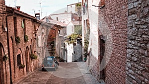 An alley of an Italian medieval village with an old car parked Gubbio, Umbria, Italy