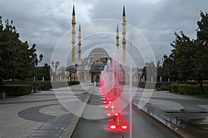 Alley of red fountains against the background of the Heart of Chechnya mosque. Grozny