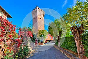 Alley and red tall medieval tower in Piedmont, Italy.