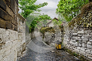 Alley with stone-stacked walls in ancient houses on cloudy day