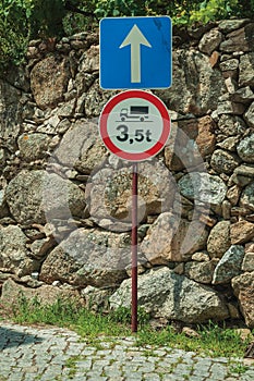Alley with stone wall and WEIGHT LIMIT AHEAD traffic sign