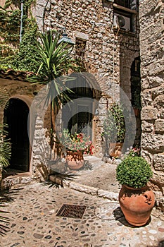 Alley with stone walls, doors and plants in Saint-Paul-de-Vence.