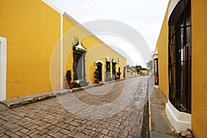 Alley surrounded by yellow buildings after rain in Izamal, Mexico