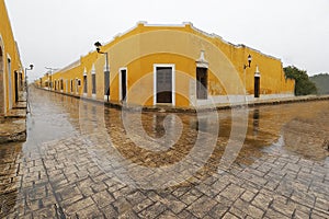 Alley surrounded by yellow buildings during the rain in Izamal, Mexico