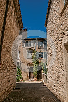 Alley view with stone walls, house and plants in Saint-Paul-de-Vence.