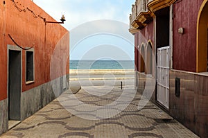 Alleyway between red houses and views of the promenade