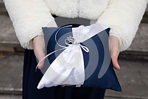 alliances wedding rings on white blue pillow in bride hands for the marriage couple