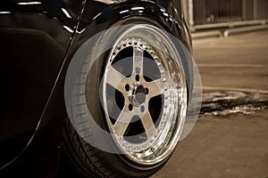 Alloy polished rims of a sports car. Wide wheels with stretched tires. Tuned low car