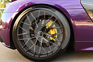 Alloy wheel with calipers and racing brakes of the sport car. Racing brake disc and low profile tyres. Race car test driving.