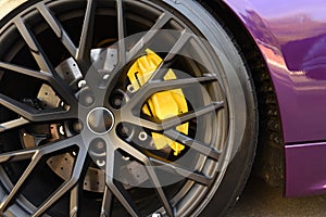 Alloy wheel with calipers and racing brakes of the sport car. Racing brake disc and low profile tyres. Race car test driving.