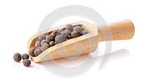 Allspice berries also called Jamaican pepper or newspice in wood scoop over white