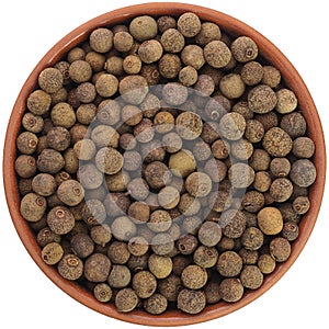 Allspice in a brown ceramic bowl isolated on white background. Isolated close-up photo of food close up from above on white