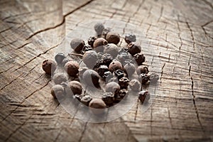 Allspice. Fragrant black pepper on wooden background