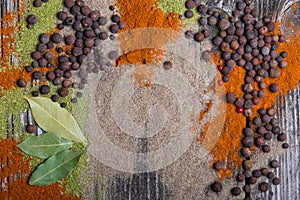 Allspice, ground black and red pepper scattered on a wooden table. Copy space