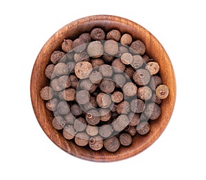 Allspice in wooden bowl, isolated on white background. Jamaican pepper, pimento berry, allspice peppercorns or myrtle